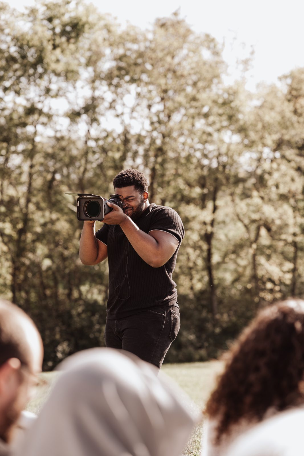 Alpha Generation videographer filming handheld at an outdoor ceremony